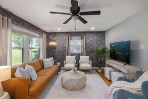 Homey vibes in the living room with plush seats, TV, and ceiling fan