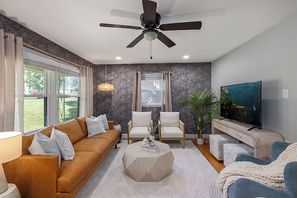 Homey vibes in the living room with plush seats, TV, and ceiling fan