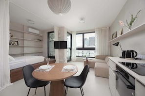 Studio with an elevated mattress, Smart TV and kitchenette with dining area.