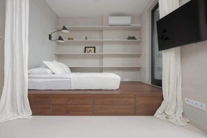 Air-conditioned lounge area with an elevated mattress and Smart TV.