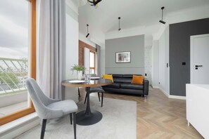 A minimalist round dining table set near tall windows, with soft natural light illuminating the area and modern chairs.