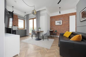 A cozy living area with modern furniture, warm wooden flooring, wall art, and a blend of natural and artificial lighting.