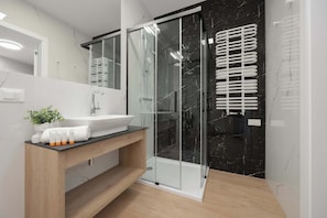 Elegant bathroom with modern and stylish shower, washing machine, towels, and welcoming toiletries set.