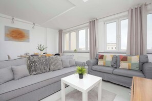 A modern living room with a grey sofa, white coffee table, and large windows letting in lots of natural light.