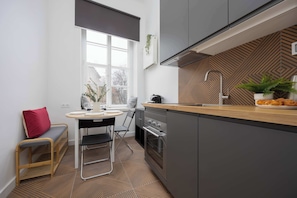 Fully equipped kitchen with induction cooktop, oven, electric kettle, coffee maker, refrigerator with freezer, toaster, dishwasher and dining area.
