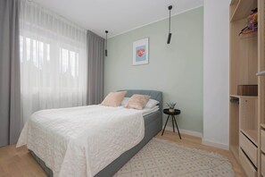 Bright, elegant bedroom with a large, comfortable bed, minimalist decor, with a large closet, bedside lamps and bedside table.