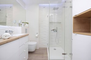 Bright, modern bathroom ith towels and shoer.
