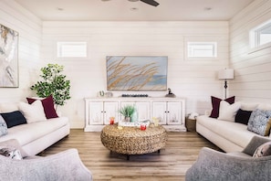 Living Room on the 1st Floor with plenty of comfortable seating around a 65" Smart TV with easy access to the Kitchen, Dining Room, Half Bath, and Backyard Oasis!