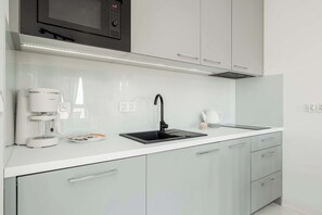 A close-up of the kitchenette with white cabinets.
