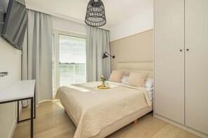 A cozy bedroom with soft beige tones, a large bed, and direct access to a balcony.