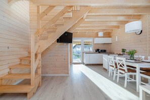 In the living room, a flat-screen TV hangs below the stairs that lead to the first floor for evening entertainment.