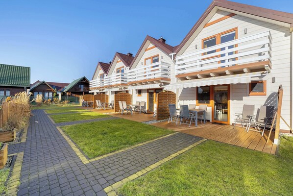 View of wooden holiday cottages with balcony and access to the garden.