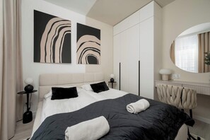 Elegant bedroom with large bed with linens, dressing table with mirror and closet