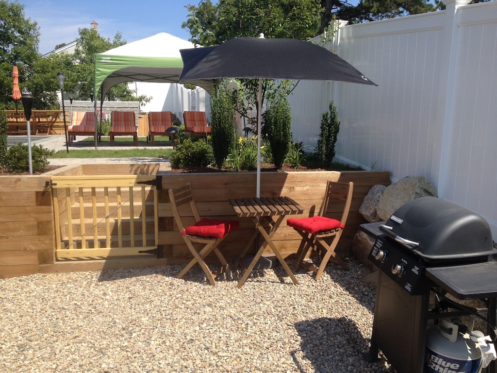 A private patio area at a vacation home with rocks underfoot and a gas grill visible