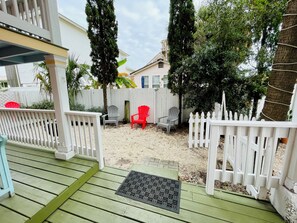 Condo's fenced-in yard with seating and charcoal grill. Photo taken from entry.