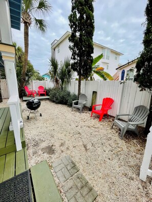 Condo's fenced-in yard & deck with seating and charcoal grill. 