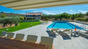 Shaded dining area by the pool. The swimming pool is heated on demand.