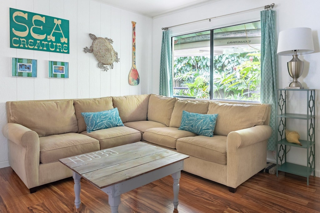 Living room of a Maui Airbnb featuring hardwood floors, turqoise accents and a turtle for decoration