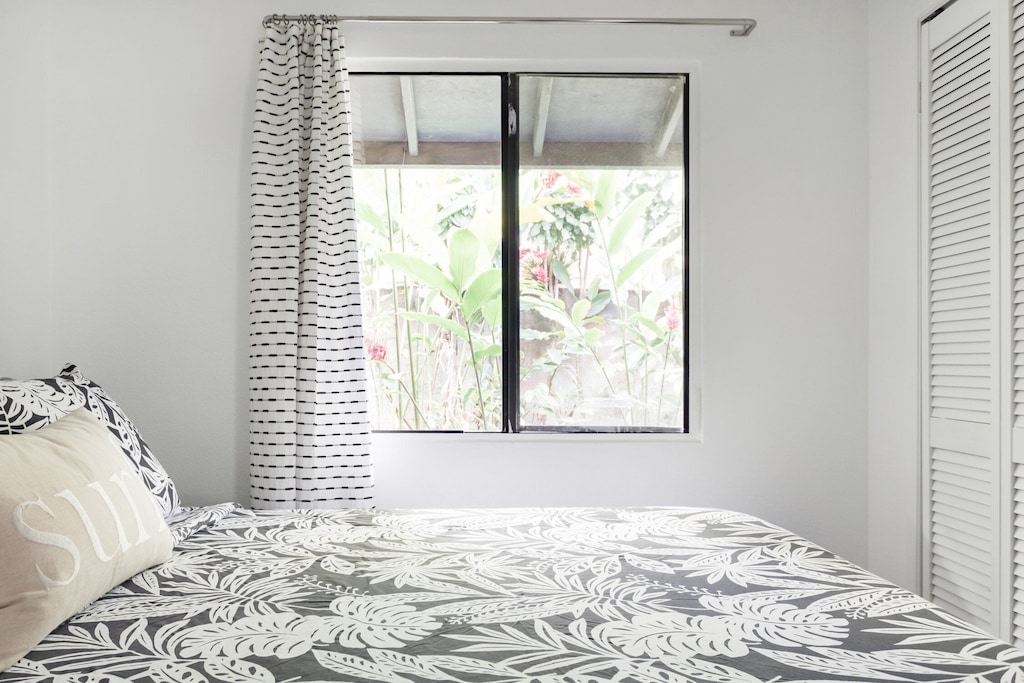 Bedroom of an Airbnb in Maui with a window view of tropical vegatation