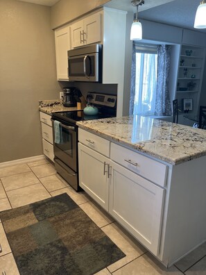 Kitchen stove is electric. One cabinet has spices. 