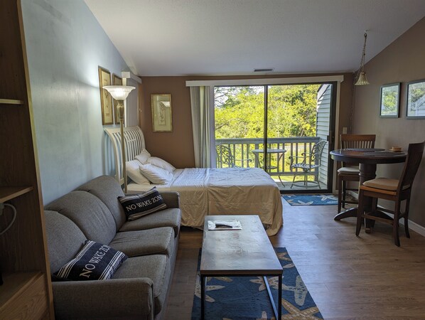 Queen bed with sliding glass door that leads out to 3rd floor balcony.