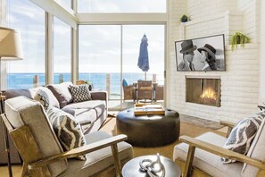 Living room has comfortable seating, 55" smart TV, fireplace and oceanfront view