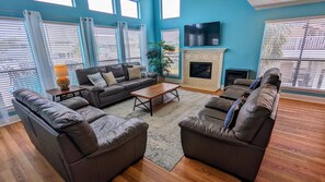 Open concept living area with floor to ceiling water views & leather sofa set.