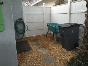 around the corner of the front patio is a hose and doggie bath 