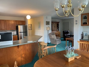 Kitchen to left behind island counter, dining in foreground, living area in back