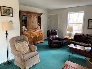 Hutch has books, games and puzzles. Two chairs and couch, door to deck in rear.