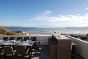 Vue de la terrasse aménagée avec table, bar, salon de jardin et barbe-cue