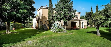 The garden is beautifully tended, with a perfect lawn and shaded areas, including a gazebo