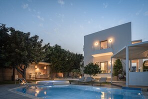 Villa view and swimming pool at sunset. 