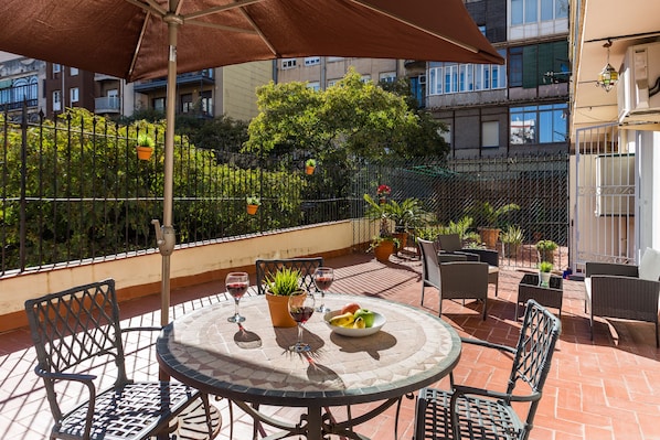 The spacious and sunny terrace looks out onto an interior urban garden