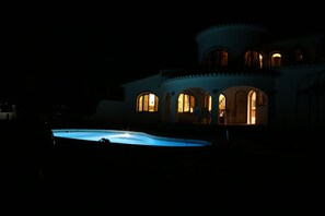 Night time view of pool and house