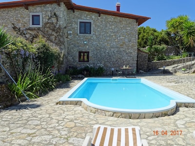 Casa de piedra con piscina y un amplio jardín.