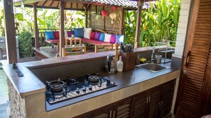 The fully equipped outdoor kitchen overlooks the garden and pool