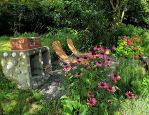 Privater Grillplatz mit Liegestühlen im Schatten der Bäume