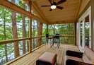 Screened in porch features large comfy chairs and a high top dining table