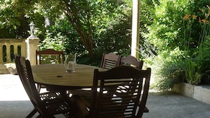 Outdoor dining sheltered from the sun,  next to kitchen overlooking the garden