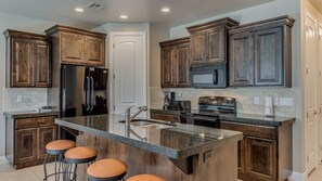 Fully stocked gourmet kitchen featuring granite countertops and extra seating at the bar