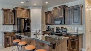 Fully stocked gourmet kitchen featuring granite countertops and extra seating at the bar
