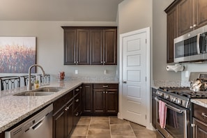 Fully stocked gourmet kitchen featuring granite countertops