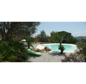 Natural lake-shaped pool in the middle of a Mediterranean garden and the suites