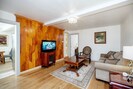 Living room with HDTV, accent wall, coffee table and cough.