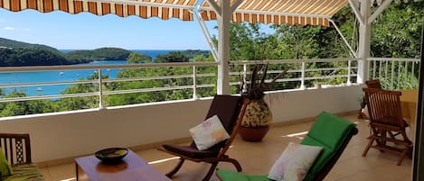 La terrasse avec vue sur la baie de l'Anse à l’Âne et la forêt à droite.