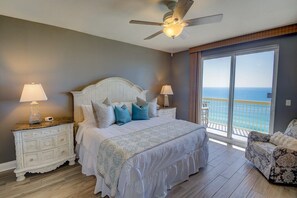 King beach bedroom with patio door to deck, blackout curtains.