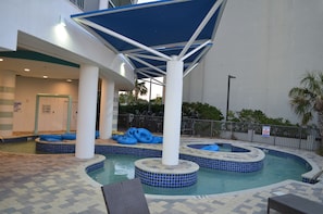 Lazy river with blue tubes under shaded canopies.