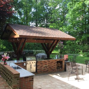 Outdoor kitchen has two grills one natural gas and one wood burning
