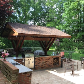 Outdoor kitchen has two grills one natural gas and one wood burning
